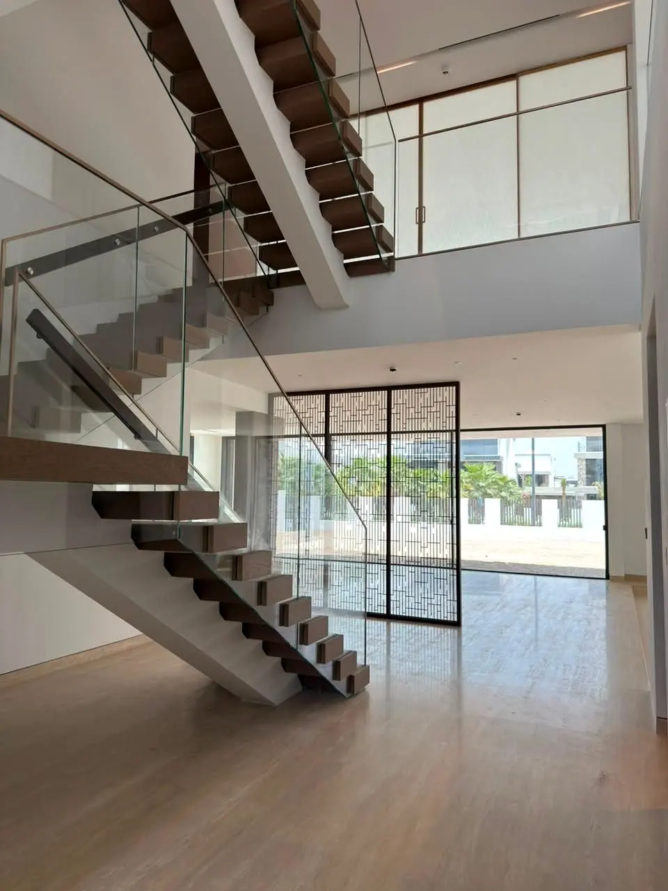 Floating stair and glass balustrade above a stone floor with garden glazing beyond