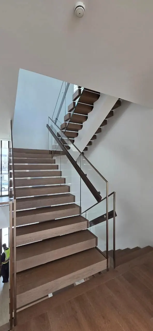Long straight stair flight with glass balustrade viewed from below