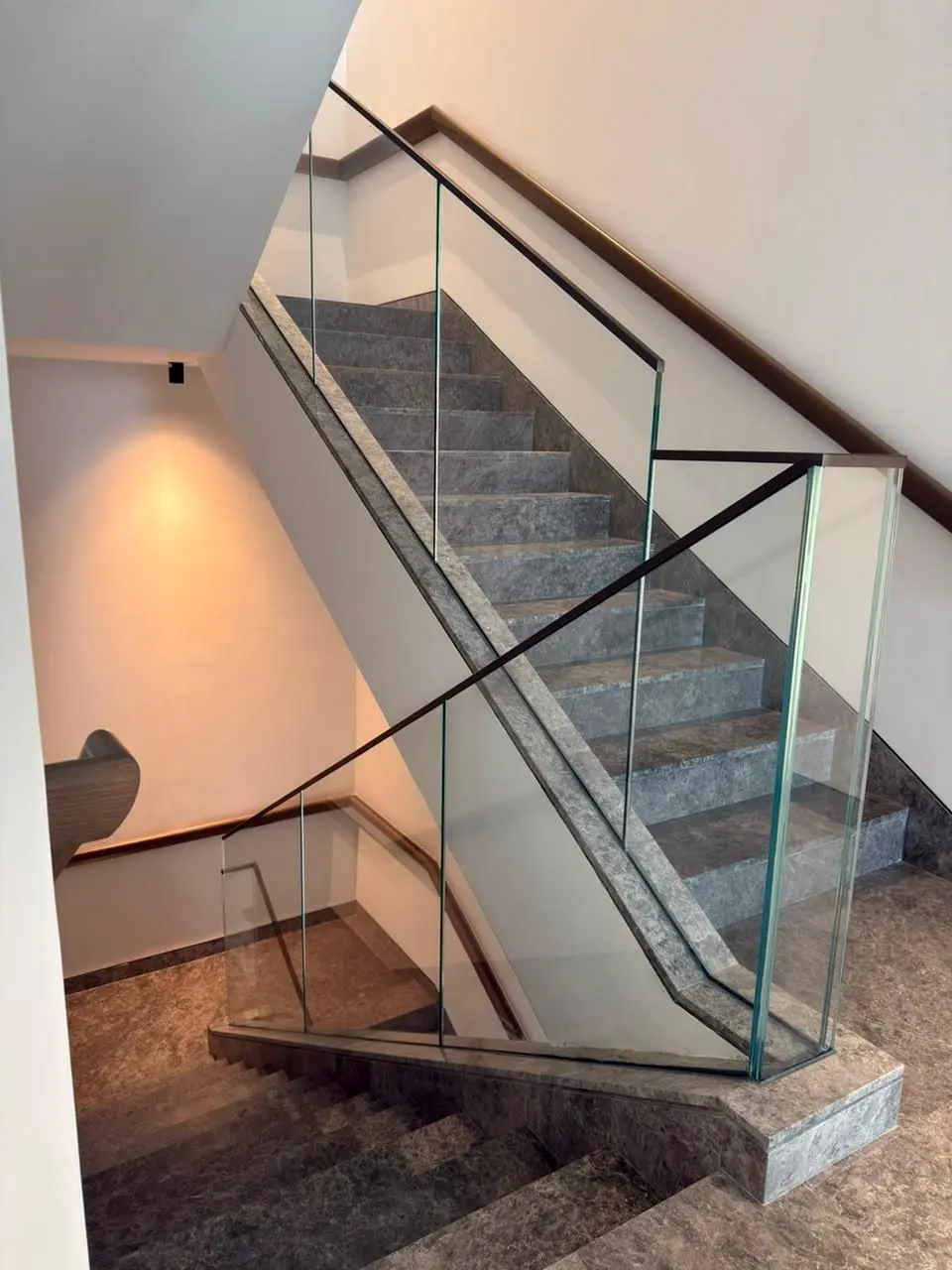 Marble stair with frameless glass balustrade and timber handrail in a stair core