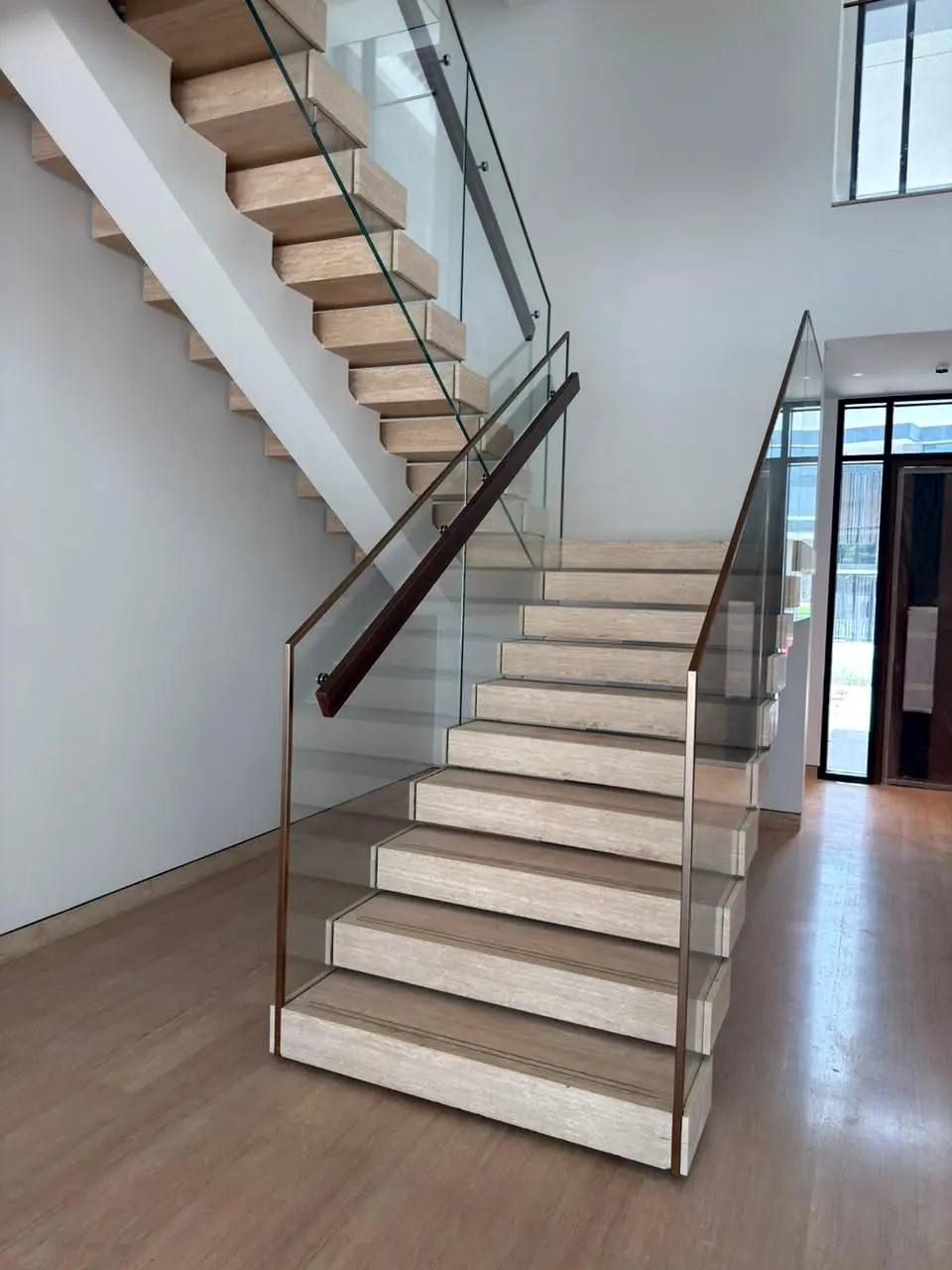 Floating stone treads and glass balustrade beside a full-height window