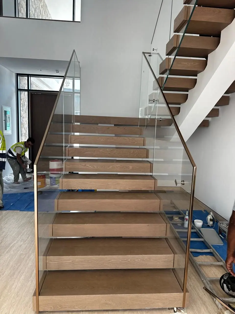Timber staircase with glass balustrade nearing handover