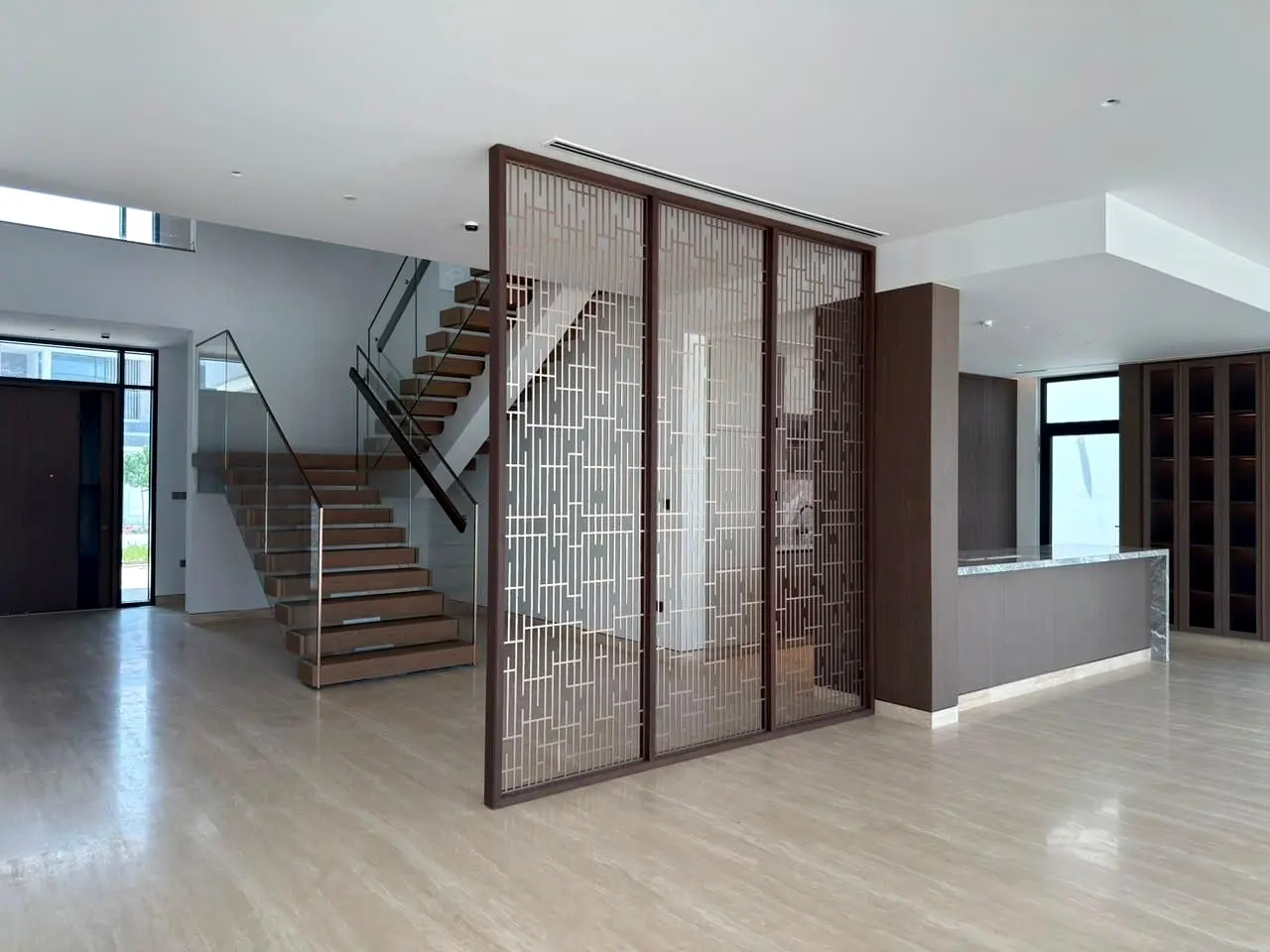 Villa hall with a bronze screen dividing the living area from the stair