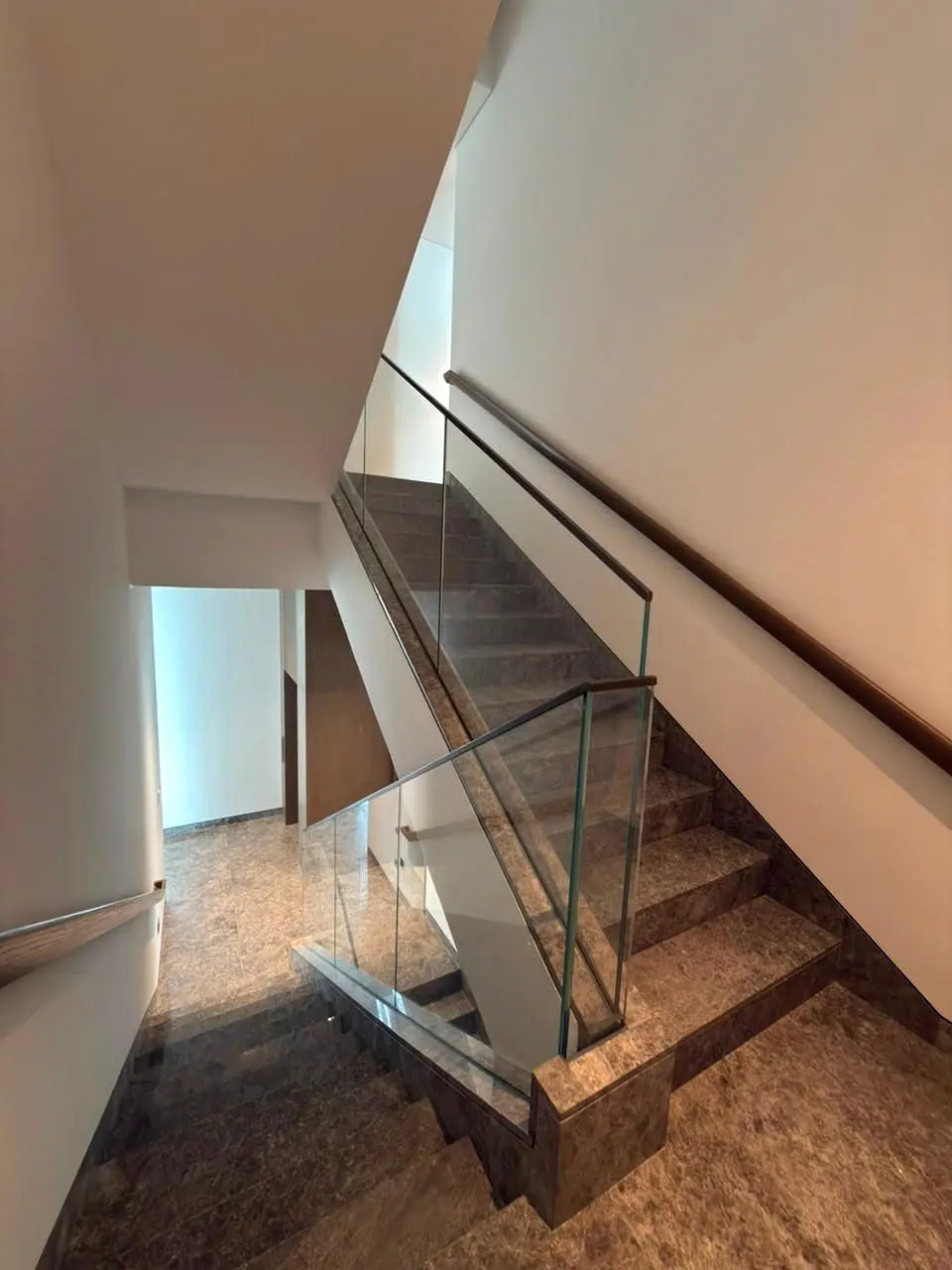 Marble stair core with frameless glass balustrade and timber handrail
