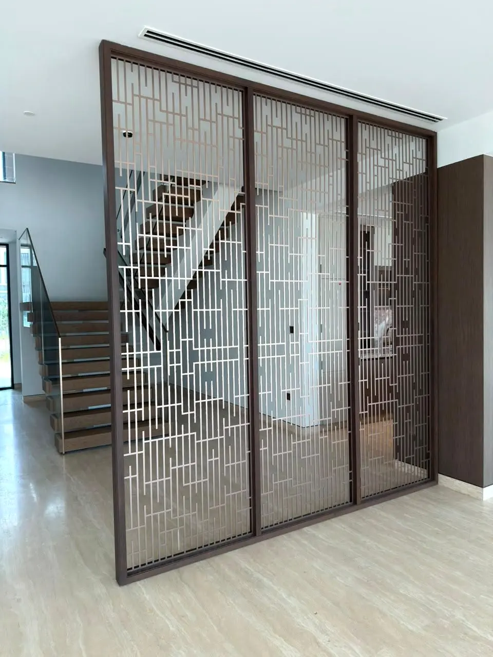Full-height bronze metal screen with the staircase visible behind