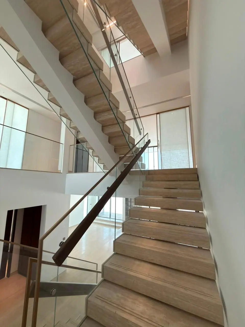 Timber stair flight with glass balustrade and bronze handrail from the landing