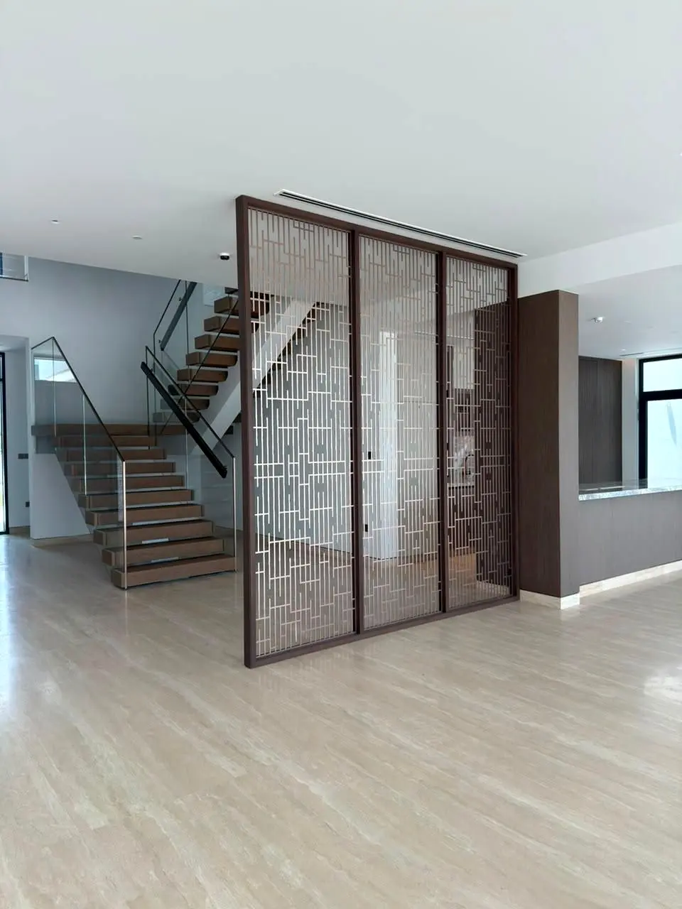 Bronze screen panels and stair in a double-height hall