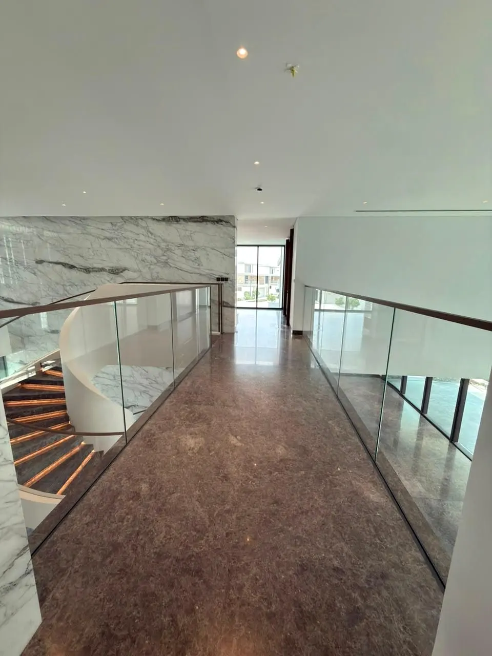 Glass balustrade along a marble-floored upper landing