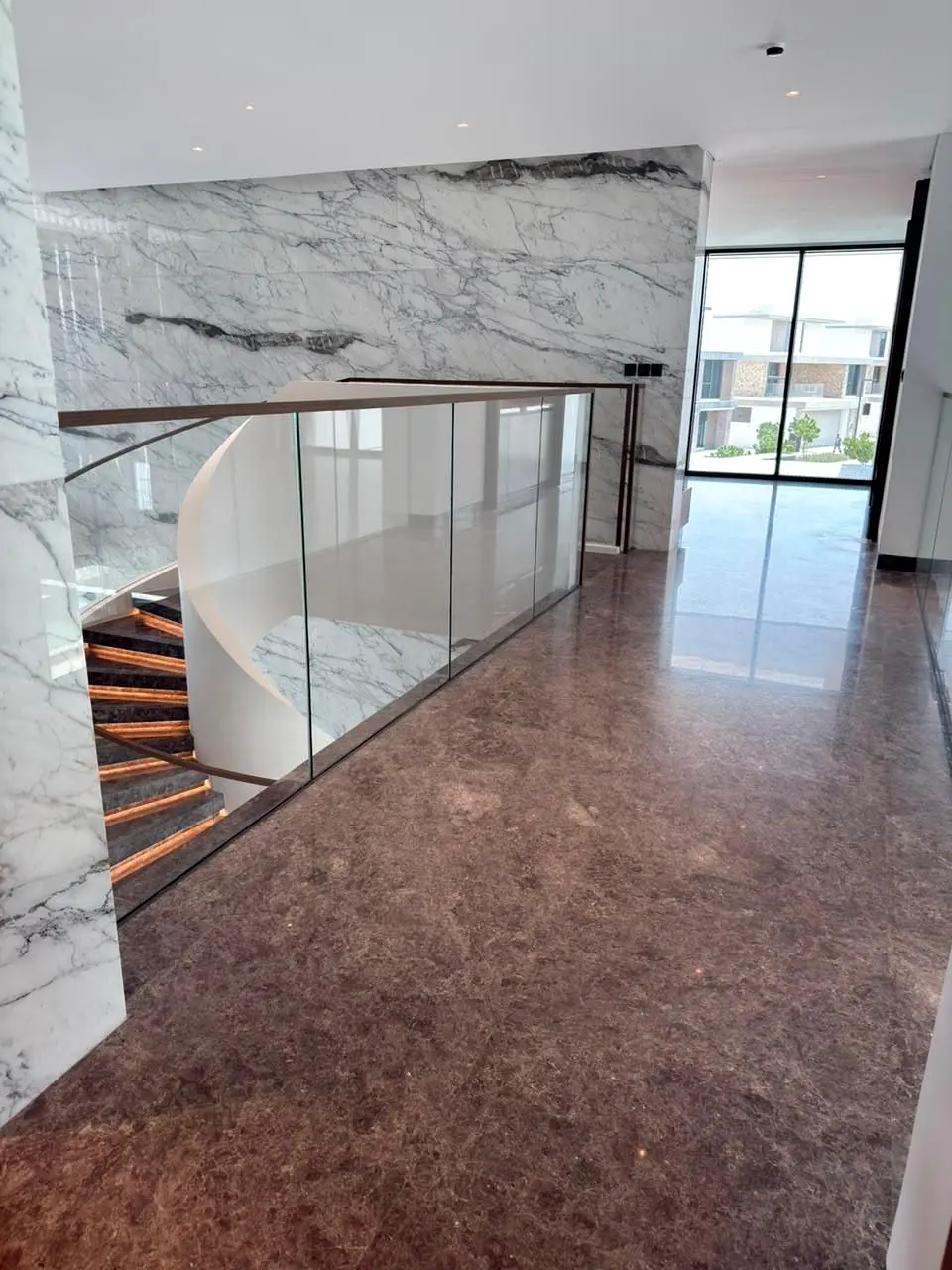 Upper landing with glass balustrade and marble feature wall