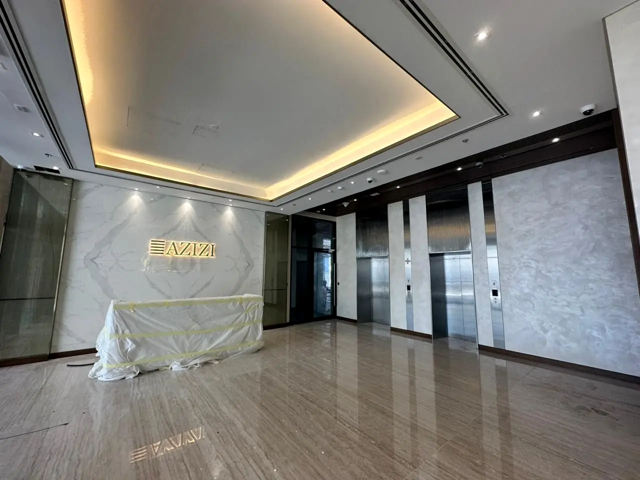 Azizi Riviera entrance lobby with a cove-lit ceiling, marble walls and lift lobby