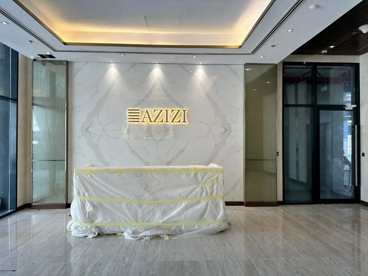 Marble feature wall with the Azizi logo behind the reception desk