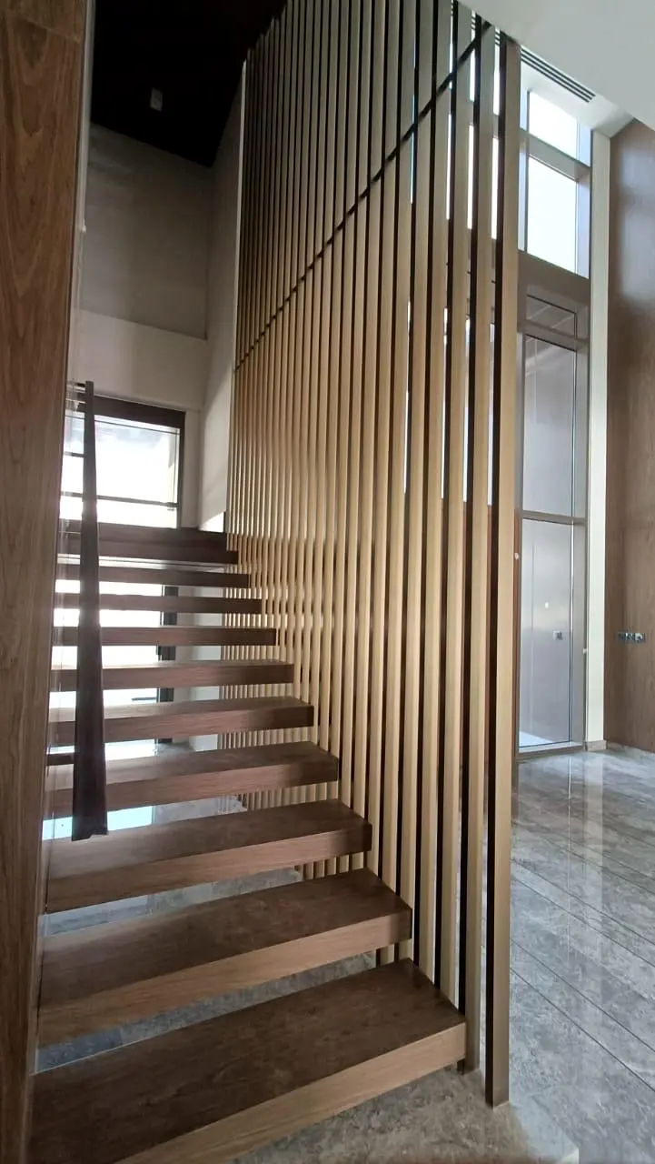 Open-riser timber staircase behind full-height vertical timber fins at Golf Place, Dubai Hills Estate