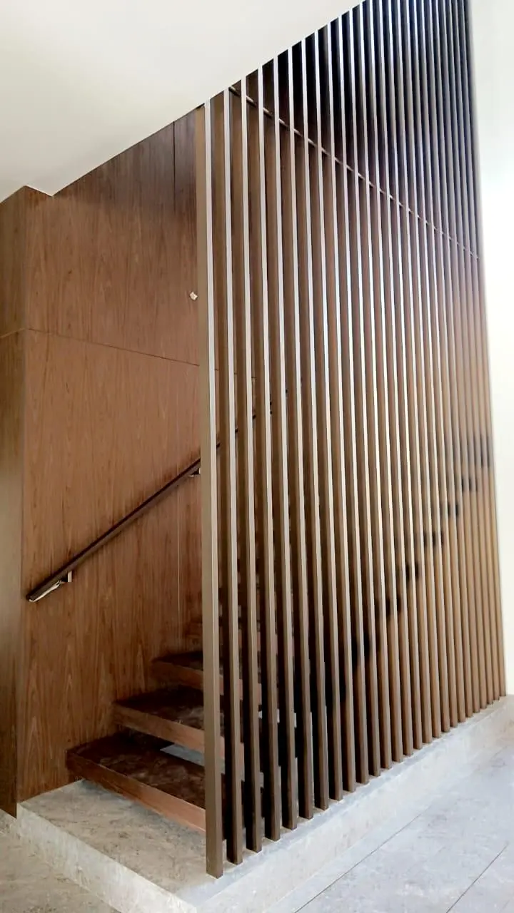 Timber-clad stair wall with a slim handrail behind vertical fins