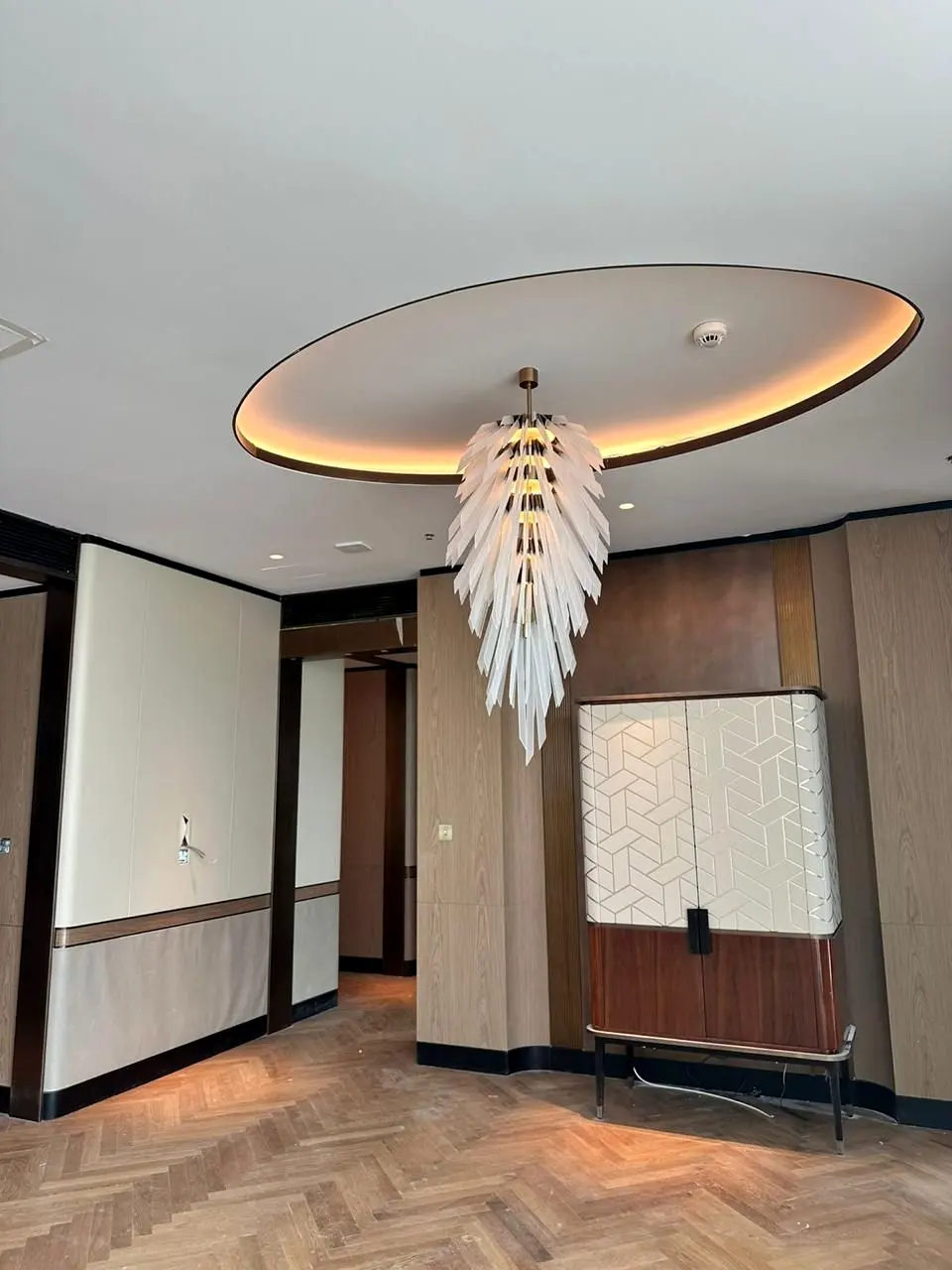 Suite entrance with lit oval false ceiling, feature chandelier and timber panelling