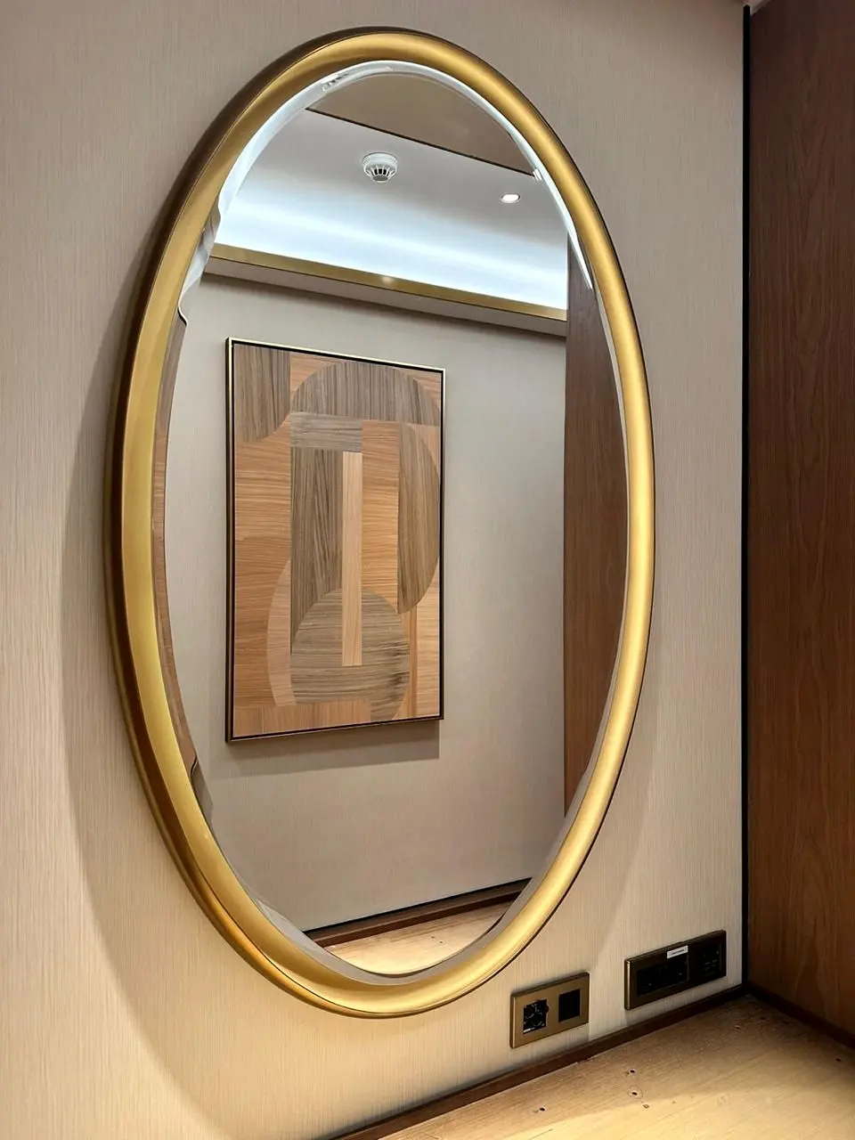 Brass-framed oval mirror on a timber-panelled wall