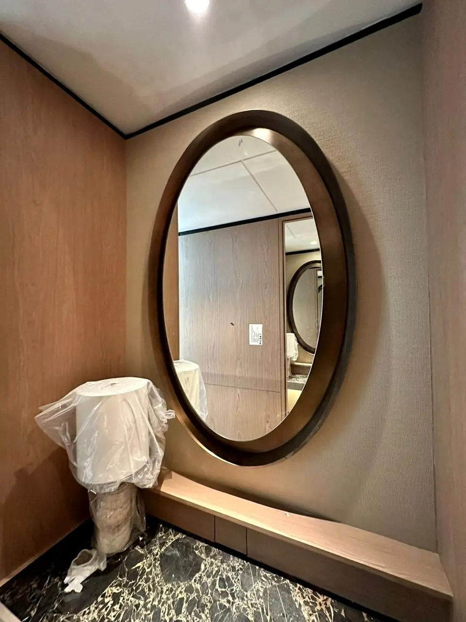 Oval timber-framed mirror above a stone vanity