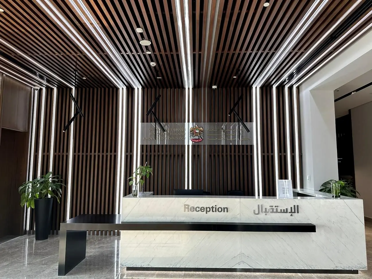 Reception with linear-lit slatted timber ceiling and a stone reception desk