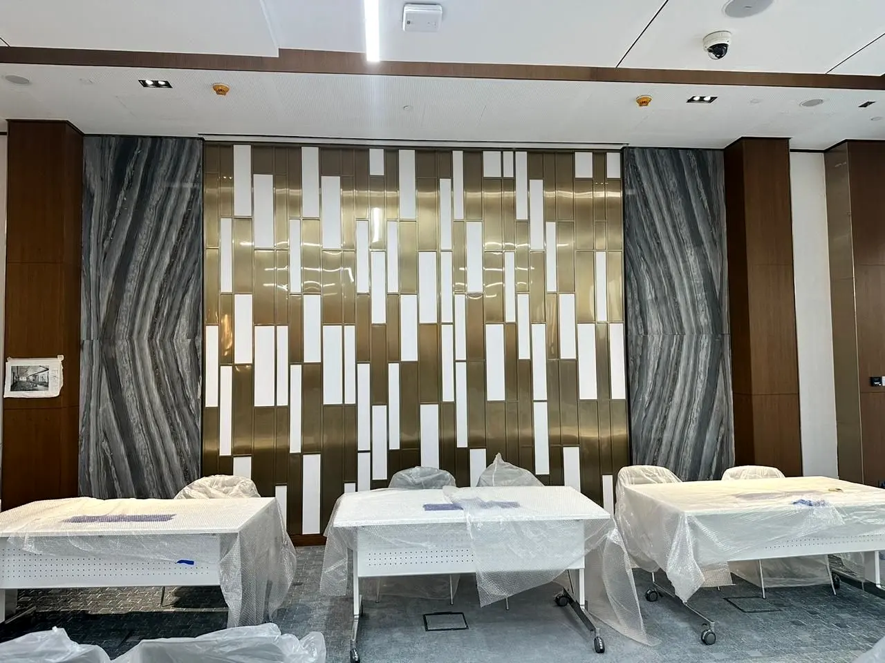Feature wall of marble panels and metal inlays behind a meeting area