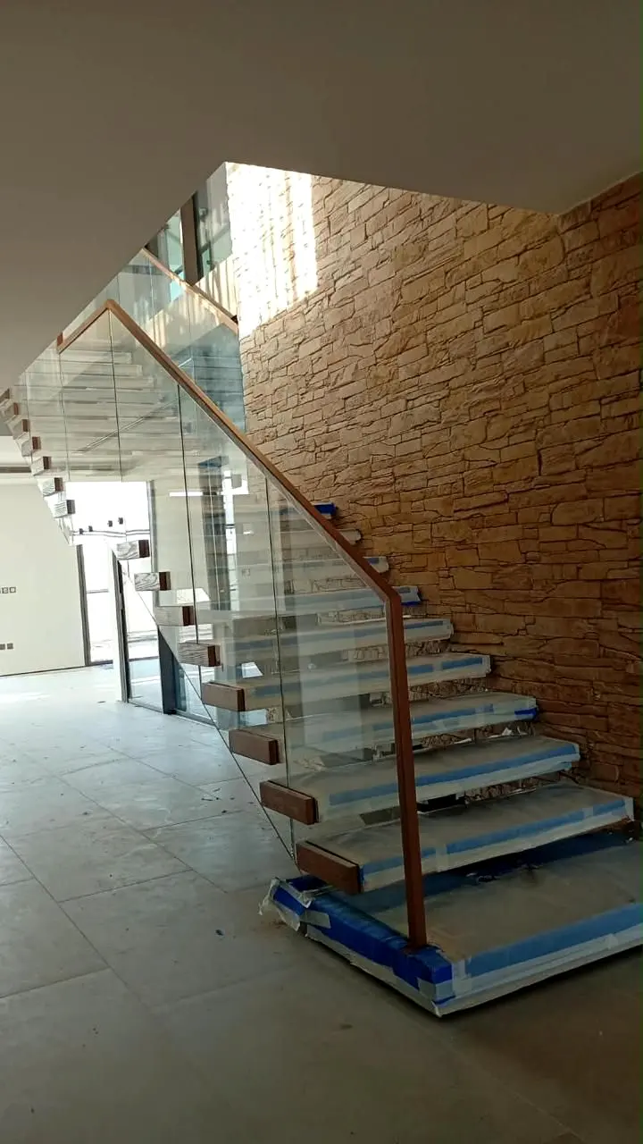 Installed glass balustrade and stair against a stone feature wall