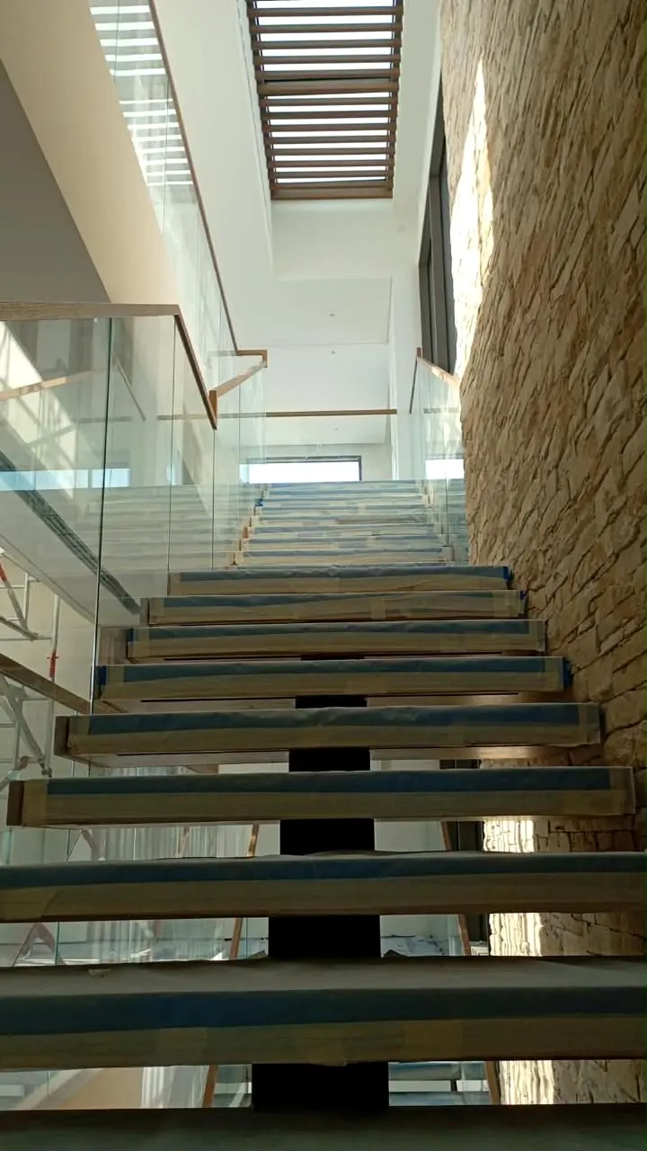 Glass balustrade stair flight against the stone feature wall
