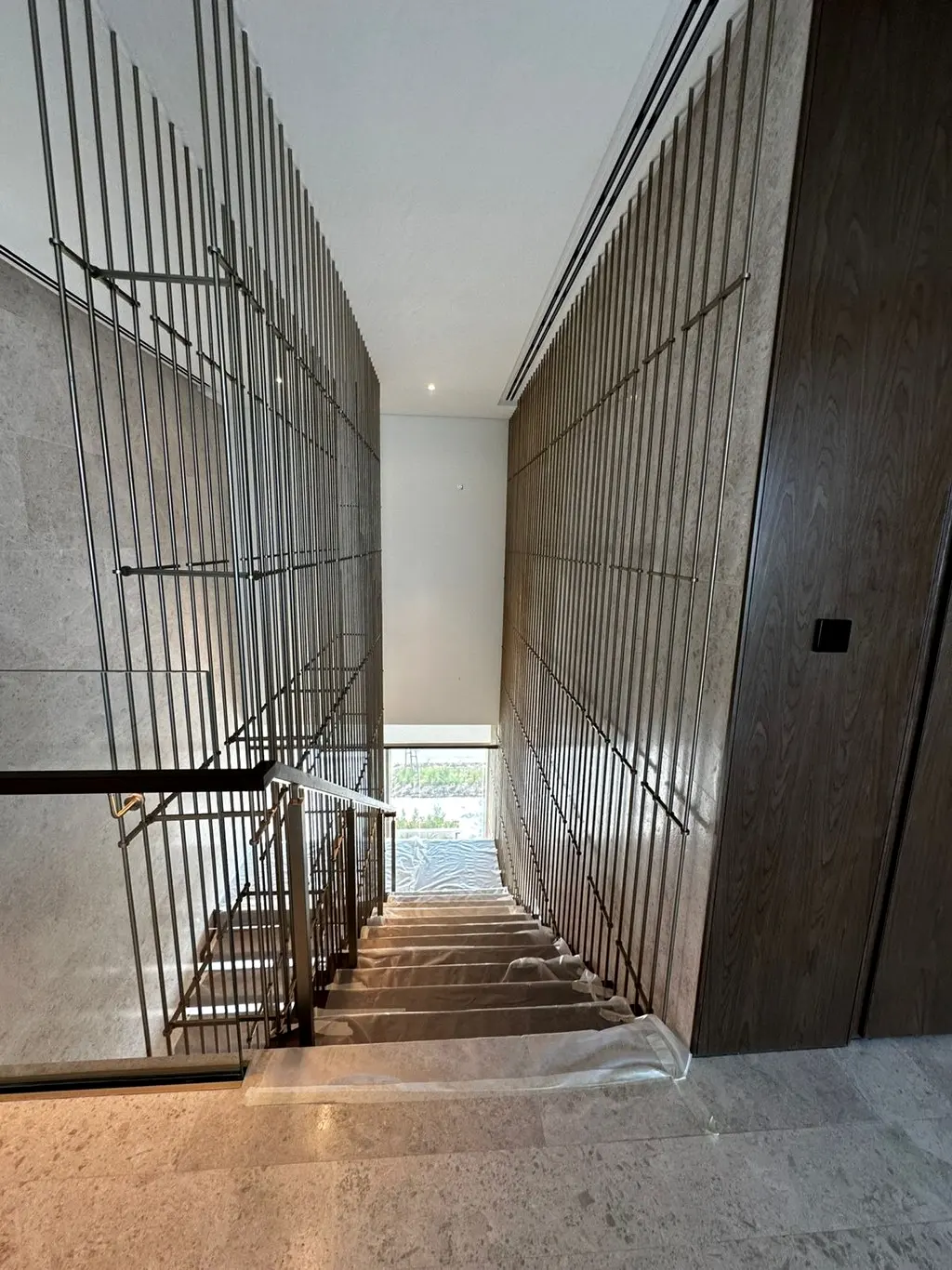 Metal screen and stair installation in progress under site protection