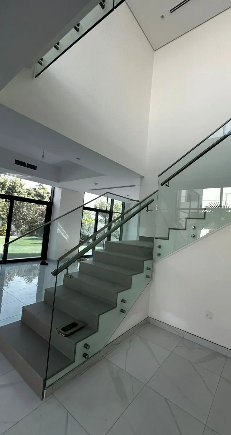 Frameless glass balustrade with a slim stainless handrail on a villa staircase