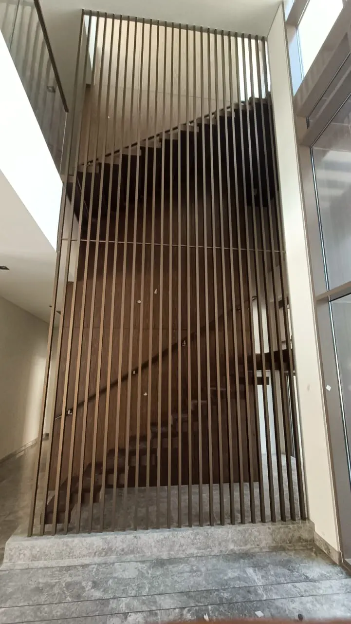 Full-height decorative metal screen enclosing a villa stair void