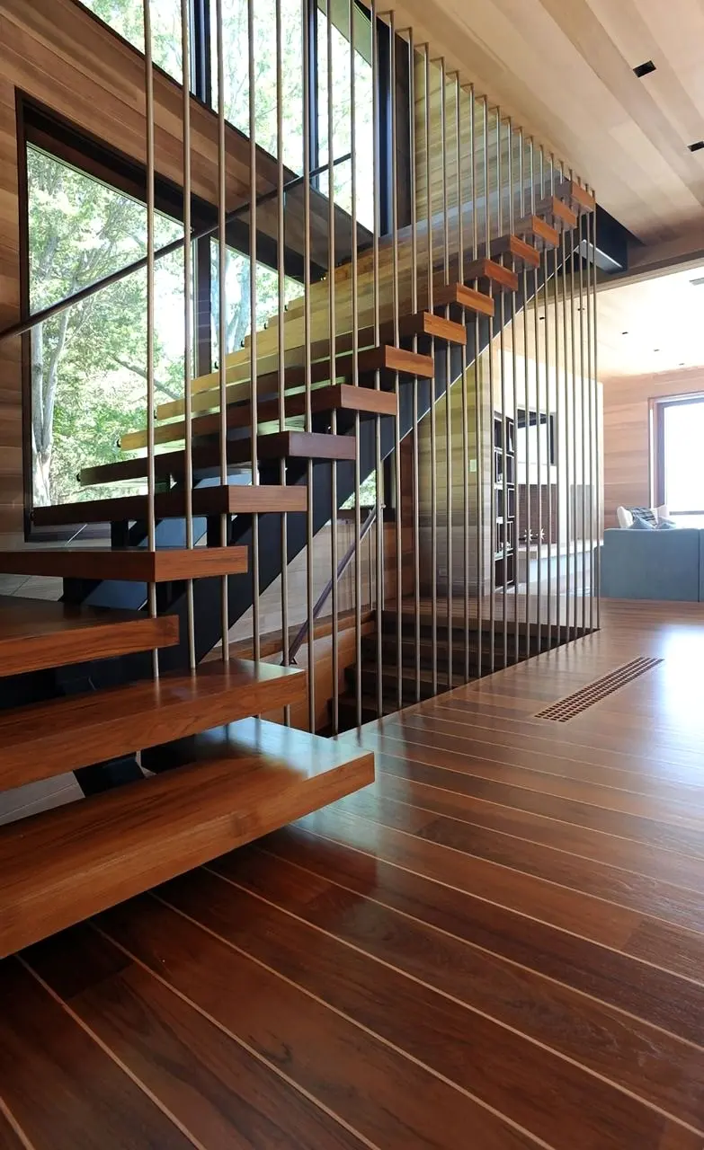 Warm timber staircase with open treads and a tensioned balustrade over a hardwood floor